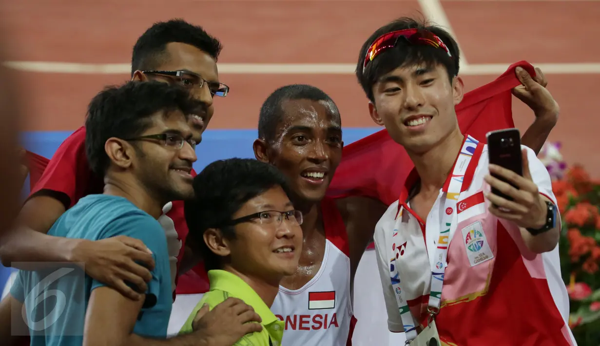  Pelari Indonesia, Agus Prayogo (kedua kanan) berfoto bersama penggemarnya usai merayakan kemenangannya di nomor lari 10.000 m putra SEA Games 2015 di National Stadium, Singapura, Rabu (10/6/2015). (Liputan6.com/Helmi Fithriansyah)