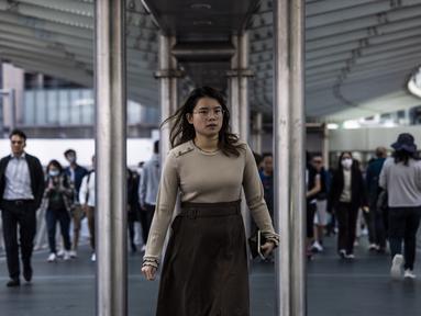 Seorang wanita berjalan melalui kawasan pusat bisnis di Hong Kong (1/3/2023). Pemerintah Hong Kong mengumumkan pelonggaran aturan Covid-19 dengan mencabut mandat penggunaan masker pada 1 Maret. Kini, warga Hong Kong bebas seperti sebelum pandemi. (AFP/Isaac Lawrence)