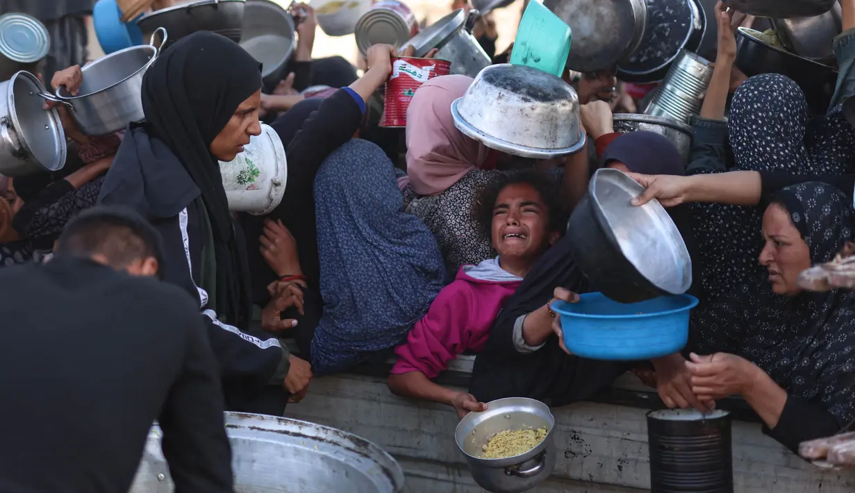 Di sebuah dapur umum di Khan Yunis, wilayah selatan Gaza, anak-anak harus bersaing dengan orang-orang dewasa untuk mendapatkan jatah makan. (BASHAR TALEB/AFP)