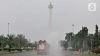 Petugas pemadam kebarakan menyemprotkan cairan disinfektan di kompleks Monumen Nasional (Monas), Jakarta, Senin (30/3/2020). Penyemprotan disinfektan ini dilakukan guna memutus rantai penyebaran virus Corona atau Covid-19 di pusat kota. (merdeka.com/Iqbal S. Nugroho)