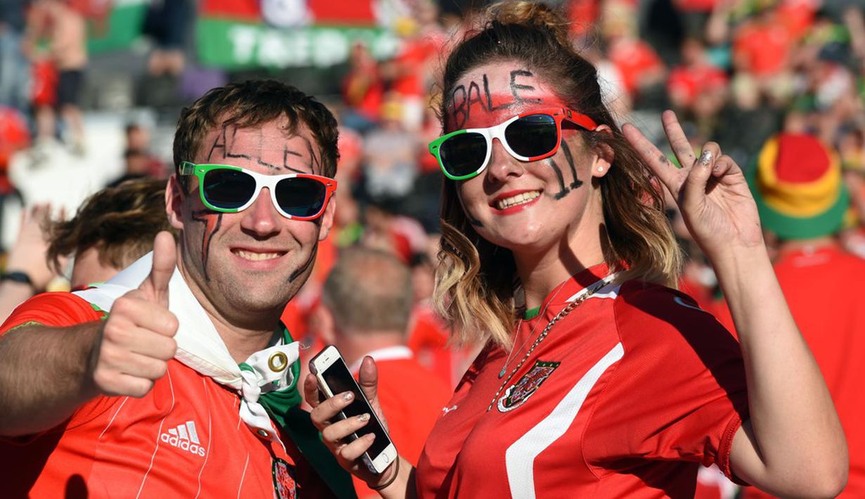 Suporter Wales pantas bergembira karena untuk pertama kalinya Wales lolos dari fase grup Piala Eropa. (AFP/Remy Gabalda)
