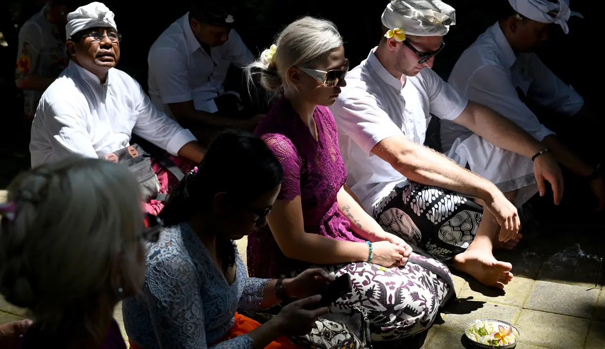 Turis Ceko, Sabina Dolezalova (tengah) dan Zdenek Slouka (dua kanan) mengikuti upacara guru piduka di Pura Beji, Ubud, Bali, Kamis (15/8/2019). Keduanya mengunggah permintaan maaf melalui akun Instagram masing-masing usai cebok menggunakan air suci di pancuran Pura Beji. (SONNY TUMBELAKA/AFP)