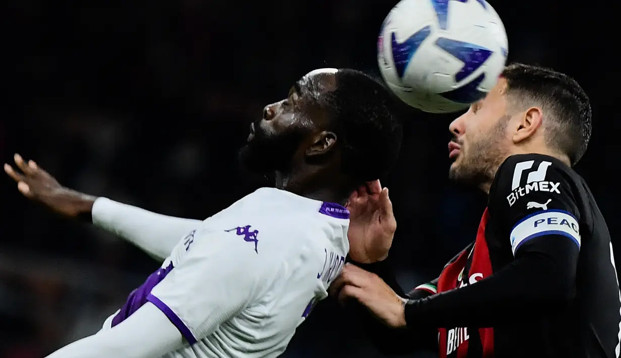 Penyerang Fiorentina Jonathan Ikone (Kiri) dan bek AC Milan Theo Hernandez melakukan sundulan pada duel pekan ke-15 Serie A 2022/2023 di San Siro, Senin (14/11/2022). AC Milan meraih kemenangan dramatis kala menjamu Fiorentina. (Filippo MONTEFORTE / AFP)