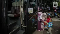 Seorang warga bersama anaknya bersiap menaiki bus tujuan mereka untuk mudik bareng gratis BUMN di kawasan Jakarta, Rabu (27/4/2022). Program mudik gratis merupakan salah satu solusi untuk mengantisipasi potensi kepadatan lalu lintas pada masa Lebaran.(Liputan6.com/Faizal Fanani)