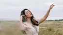 Menjadi model video klip, tidak jarang Dinda Kirana mengabadikan berbagai posenya di tempat-tempat yang indah. Seperti halnya saat di padang rumput ilalang ini. Ia pun tampil luwes dengan dress floralnya yang senada dengan suasana di sekitarnya. (Liputan6.com/IG/@dindakirana.s)