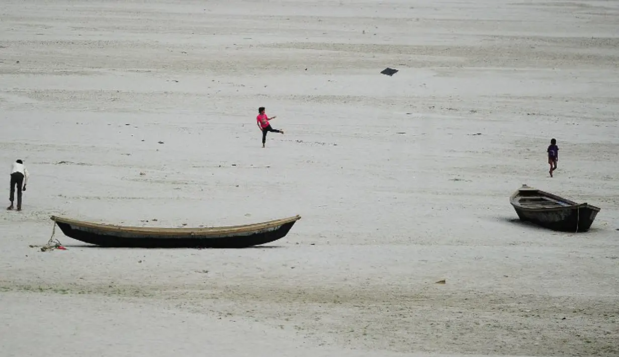Anak-anak berlarian mengejar layang-layang di sebuah sungai yang kering di Allahabad, India (3/6/2015). Cuaca panas yang melanda India tidak hanya menewaskan ratusan warga, tetapi mengubah sungai menjadi seperti lapangan.  (AFP PHOTO/SANJAY Kanojia) 