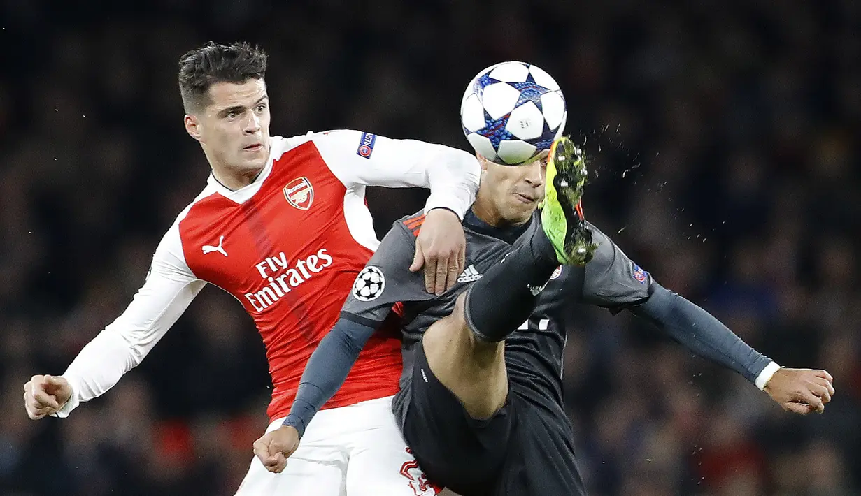 Pemain Bayern, Thiago Alcantara (kanan) berebut bola dengan pemain Arsenal, Granit Xhaka pada leg kedua babak 16 besar Liga Champions di Emirates Stadium, London, (7/3/2017). Bayer Munich menang 5-1. (AP/Frank Augstein)