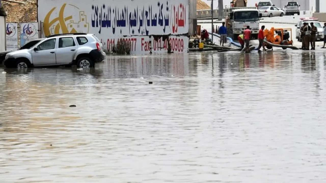 Beberapa pekerja terlihat sedang memompa air dari jalan setelah banjir menerjang Riyadh (Foto: AFP).