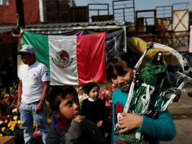 Seorang bocah membawa patung Santa Muerte atau The Saint of Death saat merayakan tahun baru di Meksiko, Minggu (1/1/2017). Warga Meksiko percaya jika berdoa kepada Santa Muerte akan membawa keberuntungan. (REUTERS/Carlos Jasso)