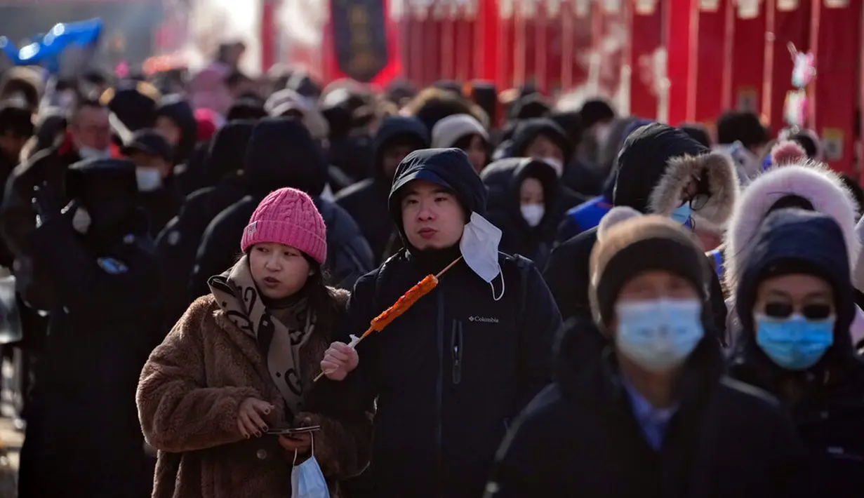 Sepasang suami istri makan sosis bakar saat orang bermasker mengunjungi pameran kuil pada hari kedua perayaan Tahun Baru Imlek di Taman Yuanmingyuan, Beijing, China, Senin (23/1/2023). Tahun Baru Imlek adalah hari libur tahunan terpenting di China. (AP Photo/Andy Wong)