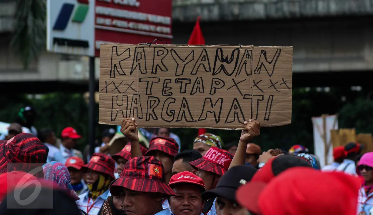 AMT (Awak Mobil Tangki) membawa poster saat melakukan mogok kerja dan unjuk rasa di Depot Pertamina Plumpang, Jakarta, Selasa (1/11). Mereka menuntut perusahaan menghapus sistem outsourcing dan membayar upah lembur mereka. (Liputan6.com/Faizal Fanani)