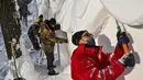 Para pria membangun rumah salju di Pameran Seni Patung Salju Internasional Harbin Sun Island menjelang Festival Es dan Salju Internasional Harbin Tiongkok ke-39 di Harbin, di provinsi Heilongjiang timur laut China (4/1/2023). (AFP/Hector Retamal)
