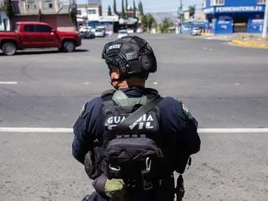 Seorang petugas polisi melakukan pemeriksaan keamanan di Jalan Raya Morelia-Patzcuaro untuk mencegah pembakaran kendaraan dan blokade jalan di negara bagian Michoacan, Meksiko, pada 23 Februari 2026. (Enrique Castro/AFP)