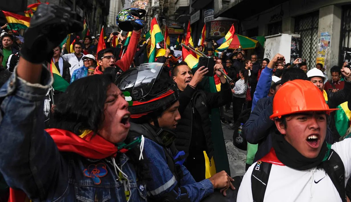 Orang-orang mengibarkan bendera Bolivia merayakan pengunduran diri Presiden Evo Morales di La Paz, Minggu (10/11/2019). Morales memutuskan mengundurkan diri buntut aksi protes yang dilatarbelakangi dugaan dirinya melakukan kecurangan dalam pemilu dalam beberapa pekan terakhir. (JORGE BERNAL/AFP)