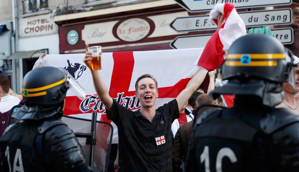 Suporter Inggris bersorak didepan petugas jelang pertandingan melawan Wales di Lille, Prancis, (15/6). UEFA mengancam akan mendiskualifikasi tim Inggris dari Piala Eropa 2016 jika para suporter membuat kerusuhan kembali. (REUTERS/Wolfgang Rattay)