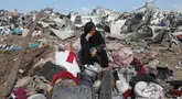 Seorang wanita Palestina yang terpaksa mengungsi duduk bersama barang-barangnya setelah serangan Israel di kamp pengungsi Deir el-Balah, Jalur Gaza tengah, pada 21 Agustus 2025. (Eyad BABA/AFP)