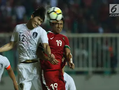 Gelandang Indonesia U-23, Hanif Abdurrauf Sjahbandi (kanan) berebut bola atas dengan pemain Korea Selatan U-23, Lee Sangmin pada laga persahabatan di Stadion Pakansari, Kab Bogor, Sabtu (23/6). Indonesia U-23 kalah 1-2. (Liputan6.com/Helmi Fithriansyah)