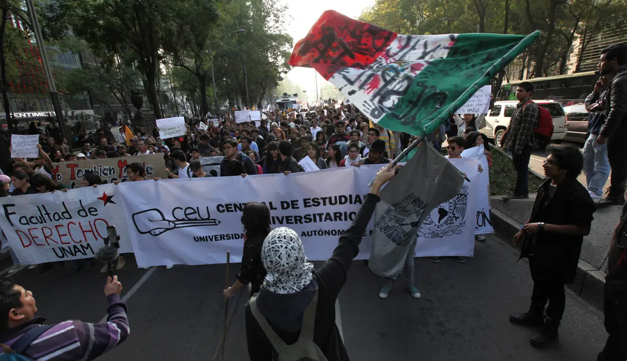 Bendera Meksiko dikibarkan saat unjuk rasa menolak kenaikan harga BBM, Mexico City, Meksiko (9/1). Akibat demonstrasi ini sekitar 1500 warga Meksiko ditahan karena melakukan penjarahan. (AP Photo/Marco Ugarte)