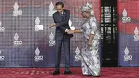 Presiden Indonesia Joko Widodo atau Jokowi menyapa Direktur Jenderal Organisasi Perdagangan Dunia (WTO) Ngozi Okonjo-Iweala saat tiba pada hari pertama Konferensi Tingkat Tinggi (KTT) G20 di Nusa Dua, Bali, Selasa (15/11/2022) pagi. Jokowi menyampaikan ucapan selamat datang di lobi depan venue utama KTT G20. (Mast Irham/Pool Photo via AP)