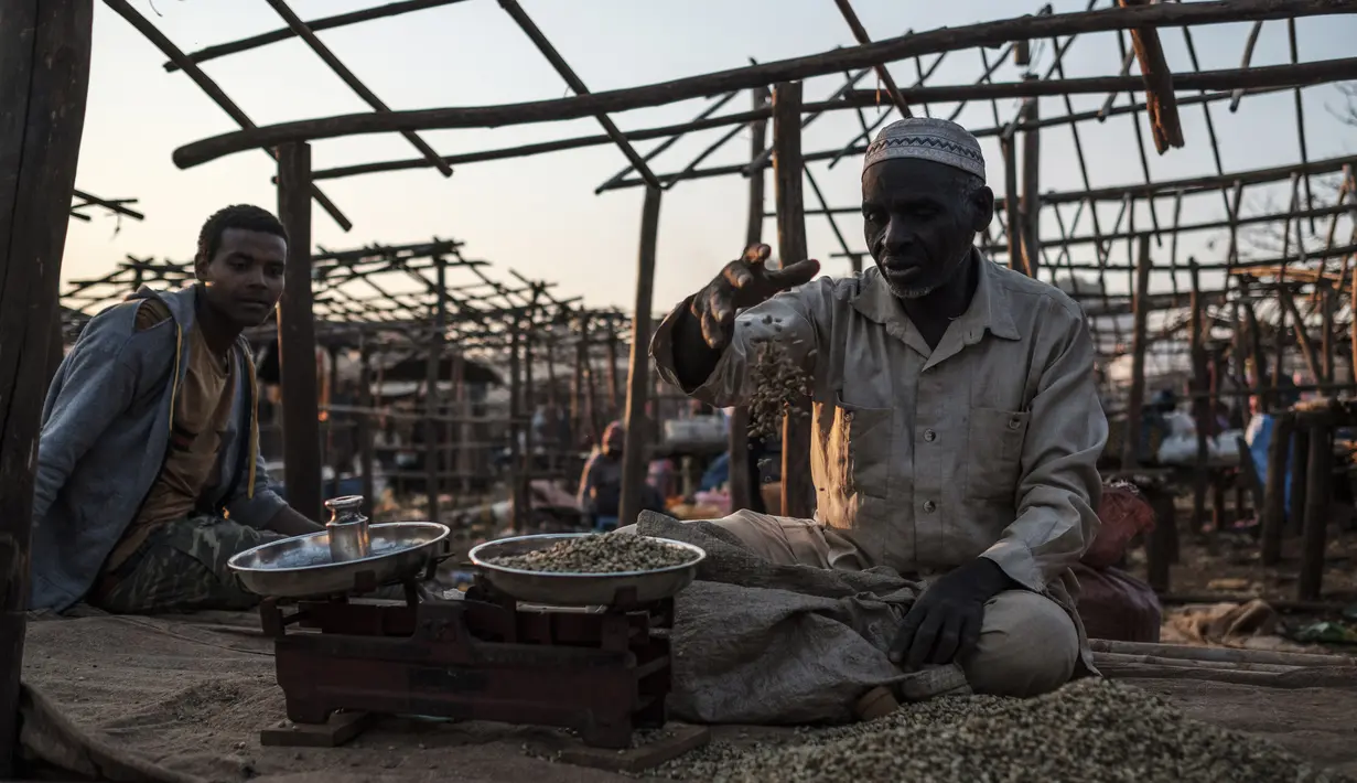 Penjual biji kopi hijau merapikan dagangannya di sebuah kios pasar lokal di Kota Asosa, Ethiopia, Rabu (25/12/2019). (EDUARDO SOTERAS/AFP)