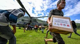 Sebelumnya, Badan Nasional Penanggulangan Bencana (BNPB) mengungkap, distribusi bantuan ke empat kabupaten di Provinsi Aceh masih sulit ditempuh lewat jalur darat. Tampak dalam foto, warga membawa bantuan yang didistribusikan oleh personel TNI AU di wilayah terdampak banjir di Kabupaten Bener Meriah, Provinsi Aceh, pada Kamis 4 Desember 2025. (CHAIDEER MAHYUDDIN/AFP)