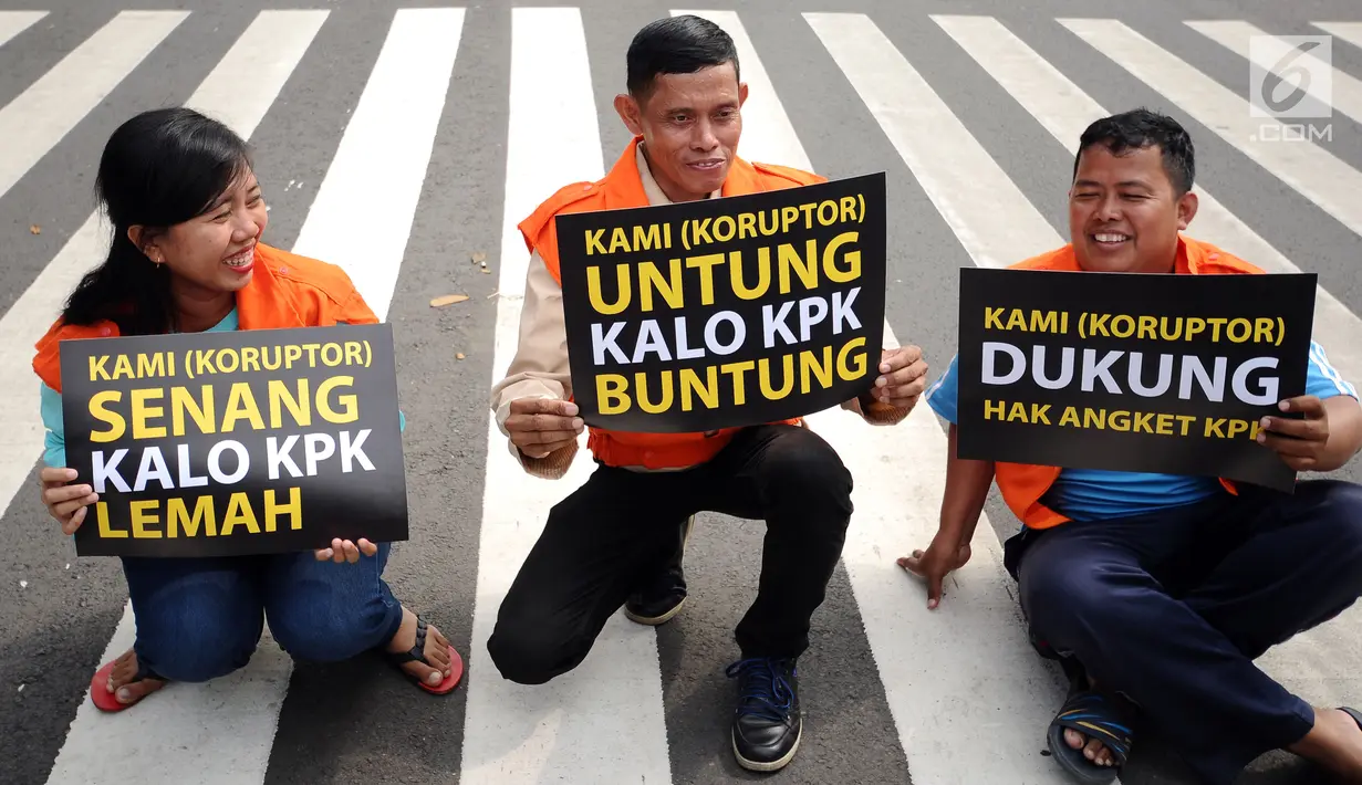 Aktivis mengangkat tulisan bertema satir usai memparodikan adegan pertemuan anggota Pansus Hak Angket KPK dengan narapidana kasus korupsi di depan Gedung KPK, Jakarta, Minggu (9/7). Mereka mengkritisi pertemuan tersebut. (Liputan6.com/Helmi Fithriansyah)