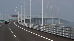 Sebuah mobil melintasi jembatan Hong Kong-Zhuhai-Macau di kota Zhuhai, China selatan, Rabu (28/3). Jembatan laut terpanjang di dunia itu dibangun dengan anggaran senilai 12 miliar pound sterling atau sekitar Rp 218,5 triliun. (AP Photo/Kin Cheung)
