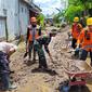 Petugas membersihkan lumpur sisa banjir di Jember. (Dian Kurniawan/Liputan6.com)