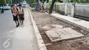 Dua pelajar melintas di samping lokasi pembangunan trotoar di Jalan Raya Ragunan, Jakarta, Rabu (12/10). Suku Dinas Bina Marga Jaksel menganggarkan Rp79 miliar untuk pembangunan dan perbaikan trotoar di 10 kecamatan Jaksel. (Liputan6.com/Yoppy Renato)