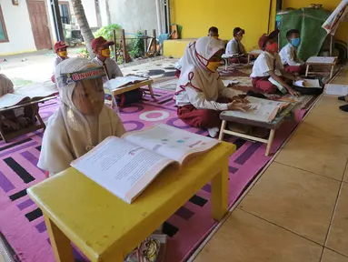 Murid kelas III SDN 02 Pondok Petir mengikuti kegiatan belajar mengajar di teras rumah salah satu siswa di Depok, Senin (31/08/2020). Sudah hampir dua minggu ini, mereka mengadakan pembelajaran secara tatap muka dengan guru yang berkeliling atas permintaan wali murid. (merdeka.com/Arie Basuki)