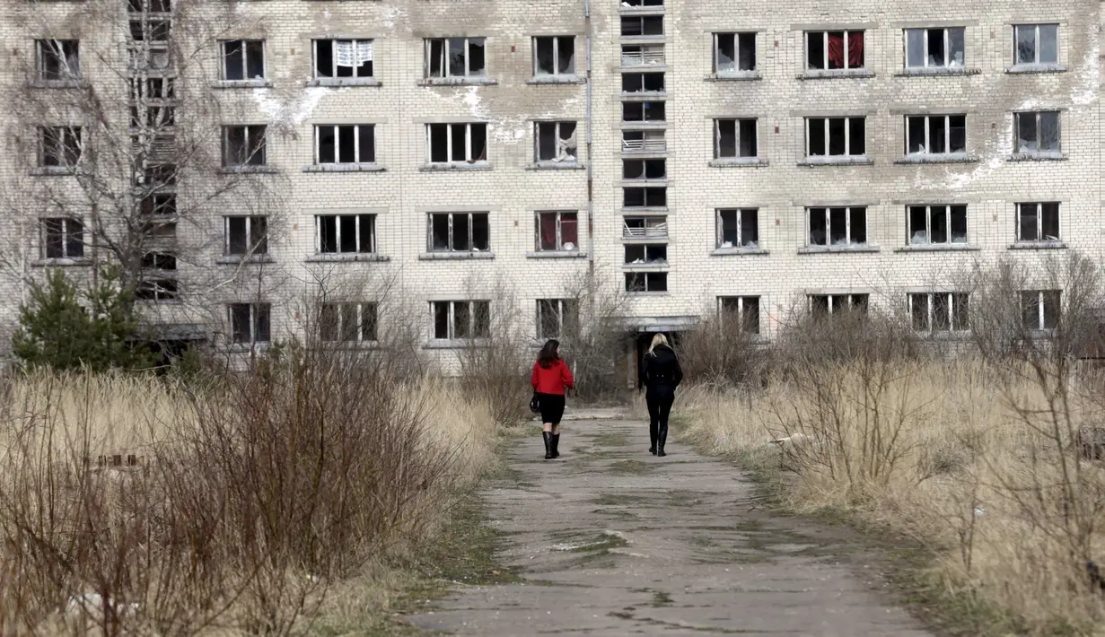 Wisatawan saat berjalan menyusuri lokasi bekas kamp militer Uni Soviet di dekat Skrunda, Latvia (9/4).Lama tak digunakan dan dirawat konon lokasi ini menjadu mengerikan dan angker. (REUTERS/Ints Kalnins)