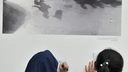 Siswa SD Negeri Menteng 01 menulis keterangan pada salah satu karya foto dalam pameran fotografi Rekam Jakarta di Taman Menteng, Kamis (29/8/2019). Kegiatan tersebut dalam rangka edukasi bagi siswa mengenal profesi foto jurnalistik. (merdeka.com/Iqbal S Nugroho)