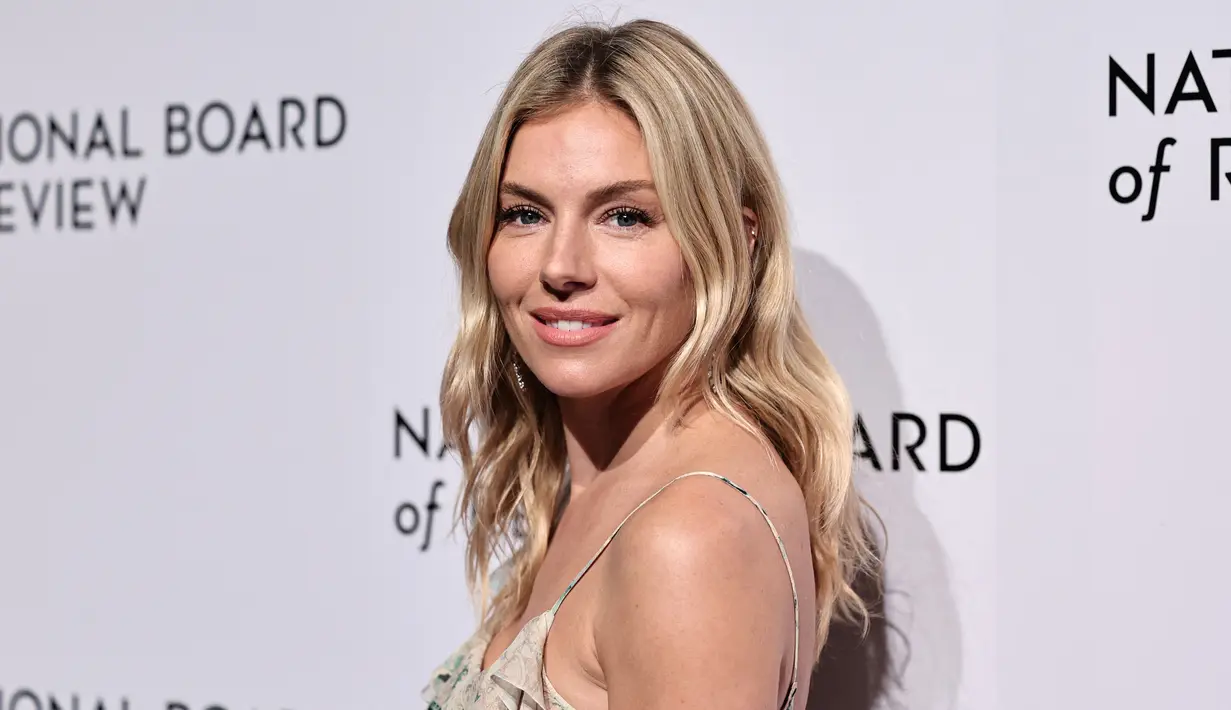 <p>Sienna Miller berpose saat tiba untuk acara National Board of Review Awards Gala di Cipriani 42nd Street di New York City pada 8 Januari 2023. Miller mengenakan rambut pirang mudanya yang dibelah di tengah dan mengalir ke bawah dalam gelombang lembut. (Jamie McCarthy/Getty Images for National Board of Review/AFP)</p>