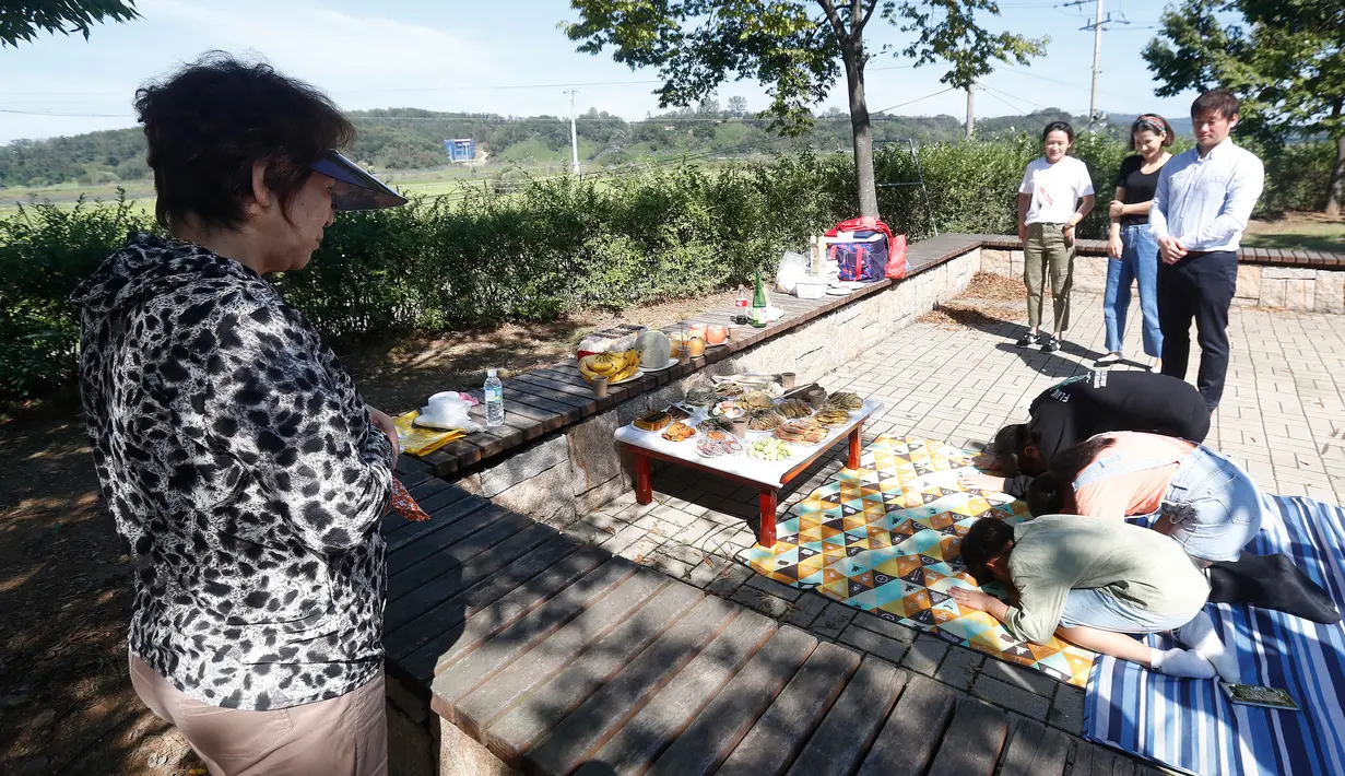Pengungsi Korea Utara, Kim Jong-ae menyaksikan anggota keluarganya memberikan penghormatan kepada leluhur untuk merayakan Chuseok di Imjingak Pavilion, Paju dekat perbatasan dengan Korea Utara, Jumat (13/9/2019). Chuseok sendiri merupakan Hari Thanksgiving di Korea. (AP/Ahn Young-joon)