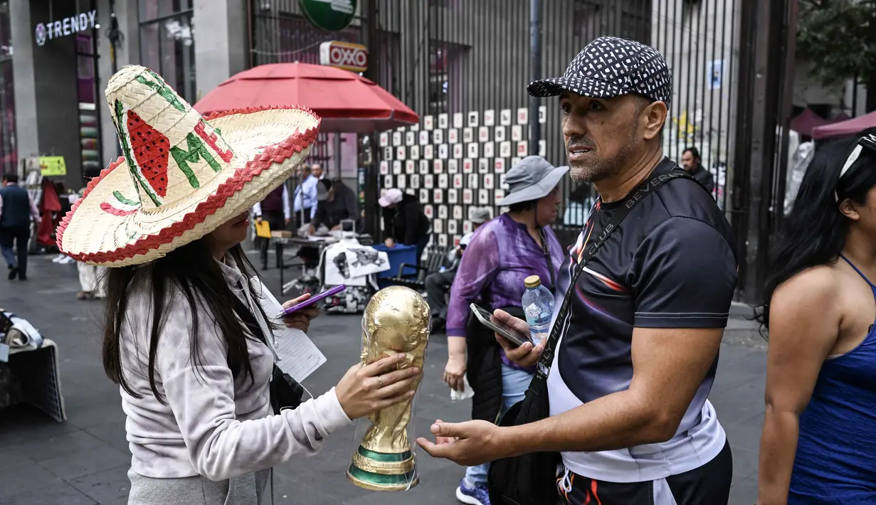 Seorang pedagang kaki lima menunjukkan suvenir berbentuk piala Piala Dunia kepada pejalan kaki di Mexico City pada Senin 8 Juni 2026. (Yuri CORTEZ/AFP)