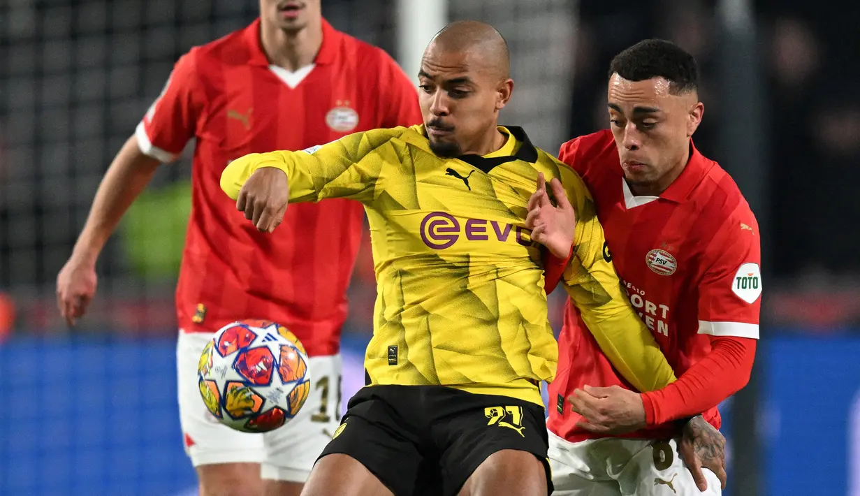 Pemain Borussia Dortmund, Donyell Malen (tengah) berebut bola dengan pemain PSV, Sergino Dest (kanan) pada laga leg pertama 16 besar Liga Champions 2023/2024 di The Philips Stadium, Eindhoven, Belanda, Rabu (21/02/2024) dini hari WIB. (AFP/John Thys)