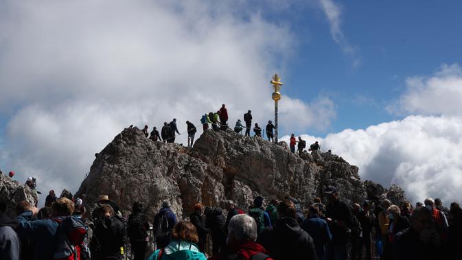 Orang-orang mengantre untuk mencapai puncak salib di puncak gunung tertinggi Jerman, Zugspitze, dekat Garmisch-Partenkirchen, Jerman pada 19 Agustus 2020. Setiap tahunnya gunung dengan ketinggian 2.962 meter tersebut membuat sekitar setengah juta pengunjung terpesona. (AP Photo/Matthias Schrader)