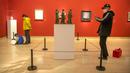 Seorang pria yang mengenakan masker mengambil foto sebuah patung di sebuah galeri di Museum Seni Nasional China di Beijing, Rabu (1/2/2023). Pengunjung terus berduyun-duyun ke museum, situs bersejarah, dan tempat wisata di ibu kota China saat periode liburan Tahun Baru Imlek berakhir. (AP Photo/Mark Schiefelbein)