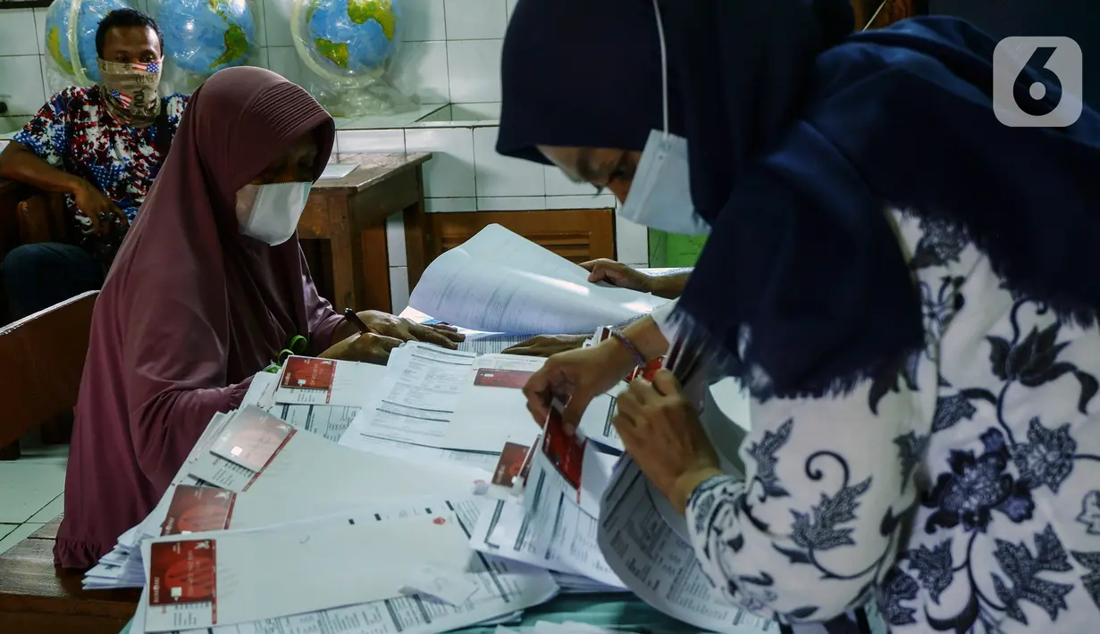 Petugas mencari data warga penerima manfaat saat pencairan bantuan sosial tunai (BST) di SDN Kembangan Utara 05 Pagi, Jakarta, Rabu (31/3/2021). Program BST sebesar Rp300 ribu dari Kemensos ini disalurkan melalui RT-RT se kelurahan Kembangan Utara melalui ATM Bank DKI. (Liputan6.com/Johan Tallo)