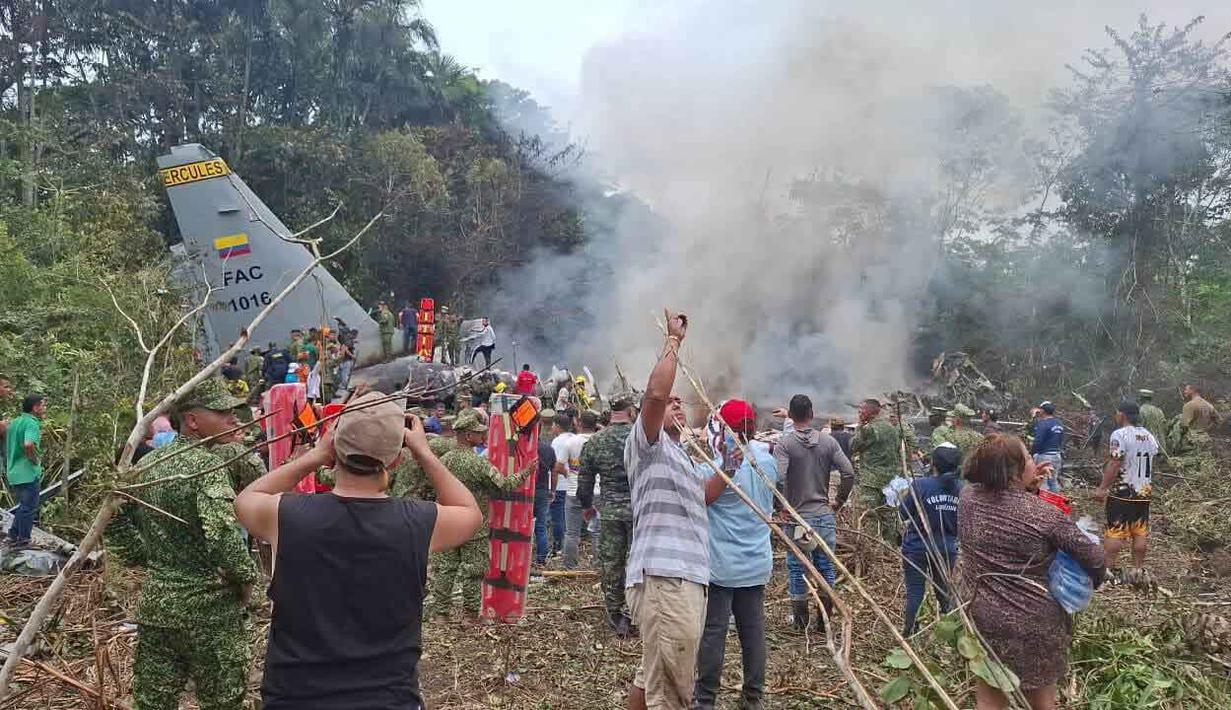 Orang-orang berdiri di sekitar pesawat kargo militer yang jatuh setelah lepas landas dari Puerto Leguizamo, Kolombia, sebuah kotamadya terpencil di provinsi Amazon Putumayo, Senin, 23 Maret 2026. Sebuah pesawat angkut militer milik Angkatan Udara Kolombia jatuh saat lepas landas di wilayah selatan Provinsi Putumayo. (MiPutumayo via AP)