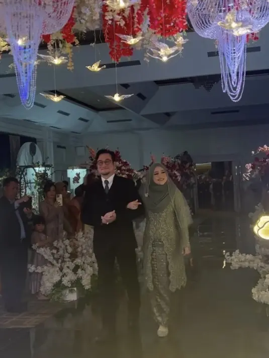 Cindy mengenakan pakaian serba hijau saat resepsi sang anak, dari atasan kebaya panjang dipadukan kain songket dan kerudung lengkap dengan veilnya. @nandito_photography.