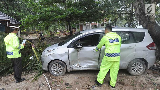 Petugas melakukan identifikasi mobil yang rusak akibat terjangan tsunami di Tanjung Lesung Beach Club, Pandeglang, Banten, selasa (25/12). Indentifikasi dilakukan untuk mencocokan kepemilikan kendaraan dengan para korban tsunami. (Merdeka.com/Arie Basuki)