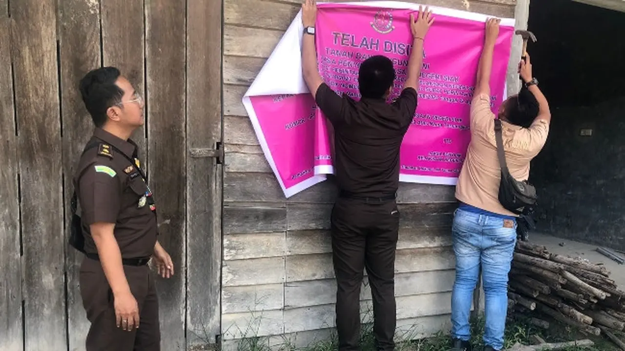 Jaksa dari Kejari Siak memasang tanda penyitaan terhadap aset tersangka korupsi pupuk bersubsidi.