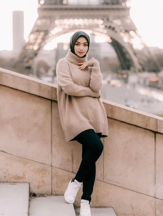 <p>Oversized turtleneck top warna nude yang dipadukan dengan skinny jeans hitam dan sepatu kets warna putih ala Citra Kirana ini chic banget buat travelling! (Instagram/citraciki).</p>