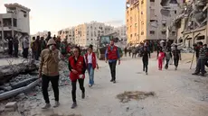 Warga bersama anggota Komite Internasional Palang Merah (ICRC) berkumpul di lokasi di mana orang-orang sedang menggali dengan ekskavator untuk mencari korban serangan Israel di antara reruntuhan bangunan di Khan Yunis, bagian selatan Jalur Gaza, pada 17 Oktober 2025. (Omar AL-QATTAA/AFP)