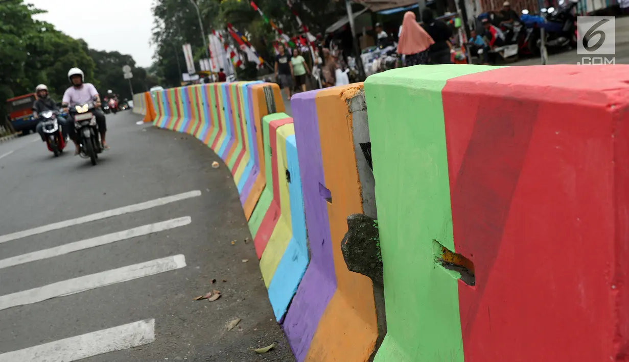 Pengendara melintasi di sisi pemisah jalan di Jalan Raya Ragunan sekitar Pasar Minggu, Jakarta, Selasa (24/7). Di kawasan ini pemisah jalan di cat warna warni sehingga terlihat lebih semarak. (Liputan6.com/Helmi Fithriansyah)