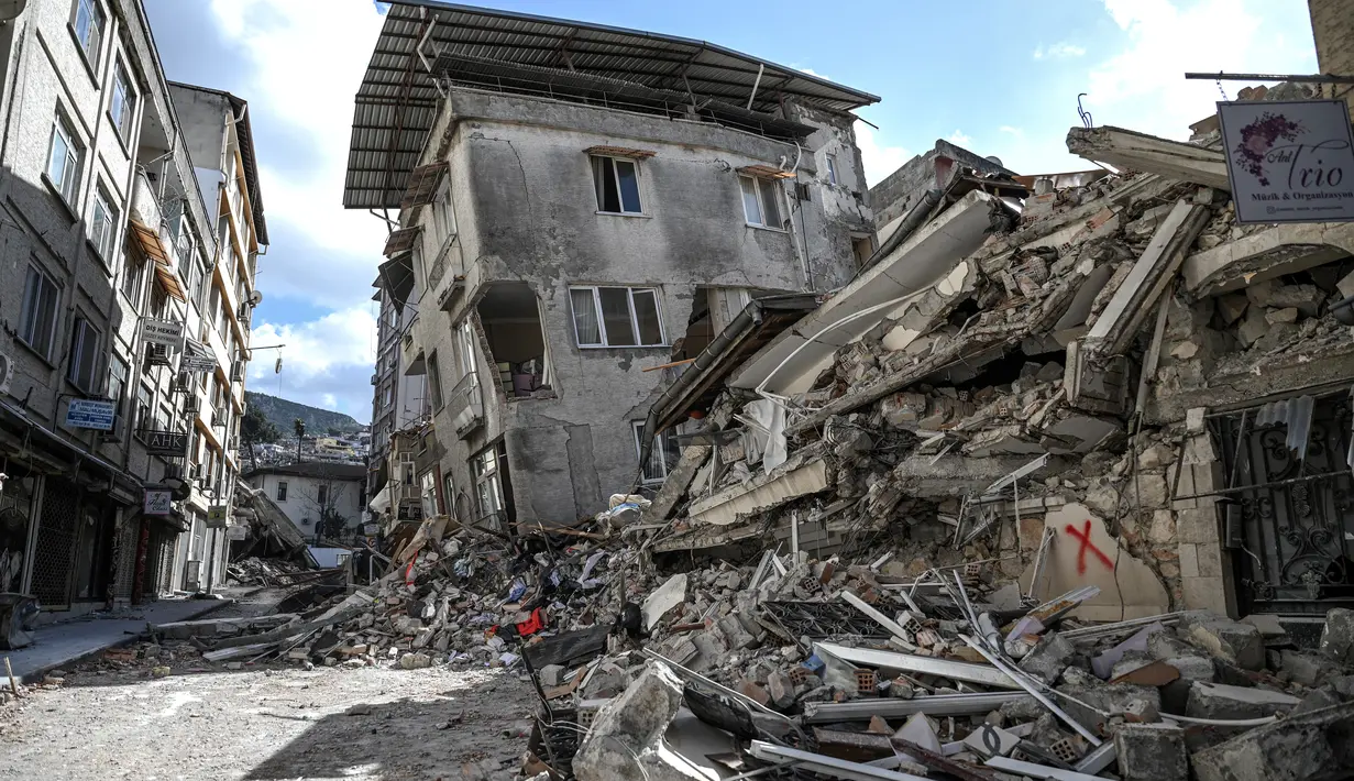Gambar ini memperlihatkan bangunan yang hancur di Hatay pada 6 Maret 2023, satu bulan setelah gempa besar melanda Turki tenggara. Gempa bumi besar berkekuatan magnitudo 7,8 mengguncang sebagian besar Turki dan sebagian Suriah pada 6 Februari 2023, menewaskan lebih dari 50.000 orang di kedua negara, dengan sekitar 46.000 di pihak Turki. (OZAN KOSE / AFP)