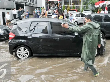 Petugas mengatur lalu lintas kendaraan yang melintas di Jalan Teuku Cik Ditiro, Jakarta, Selasa (30/8). Jalan Teuku Cik Ditiro tergenang air akibat hujan deras yang mengguyur Jakarta siang tadi. (Liputan6.com/Yoppy Renato)