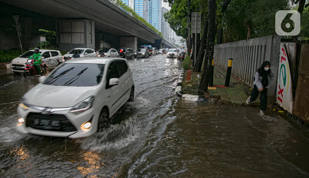Kendaraan melintasi genangan air di Jalan Gatot Subroto, Jakarta, Kamis (18/2/2021). Hujan deras yang mengguyur wilayah Jakarta menyebabkan terjadinya genangan di beberapa ruas jalan, meski begitu sejauh ini kendaraan masih dapat melintas. (Liputan6.com/Faizal Fanani)