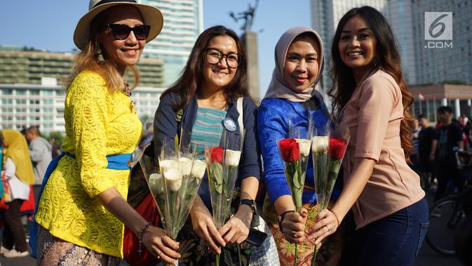 Relawan memegang bunga mawar untuk dibagikan ke pengunjung car free day di kawasan Bundaran HI, Jakarta, Minggu (30/6/2019).  Aksi 1000 bunga mawar itu sebagai bentuk rasa syukur atas kemenangan pasangan Jokowi-Ma'ruf Amin di Pilpres 2019. (Liputan6.com/Immanuel Antonius)